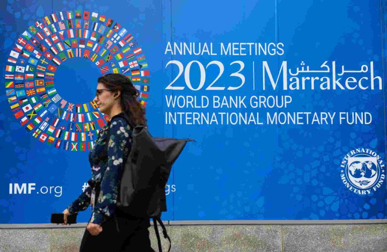 A pedestrian walks past a billboard announcing the World Bank Group and International Monetary Fund annual meetings, on the side of the International Monetary Fund headquarters in Washington D.C. on October 5, 2023.MANDEL NGAN / AFP VIA GETTY IMAGES