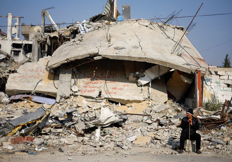 Ziad Mansour, a neighbour of the Abu Aweidah family, sits next to writing painted on a wall amid the rubble of the family's house, which was destroyed in a deadly Israeli strike amid the ongoing conflict between Israel and the Palestinian Islamist group Hamas, in Rafah, Gaza Strip, January 9, 2024. The writing reads: "Children remaining under the rubble, Oman, Abdullah and Massa"