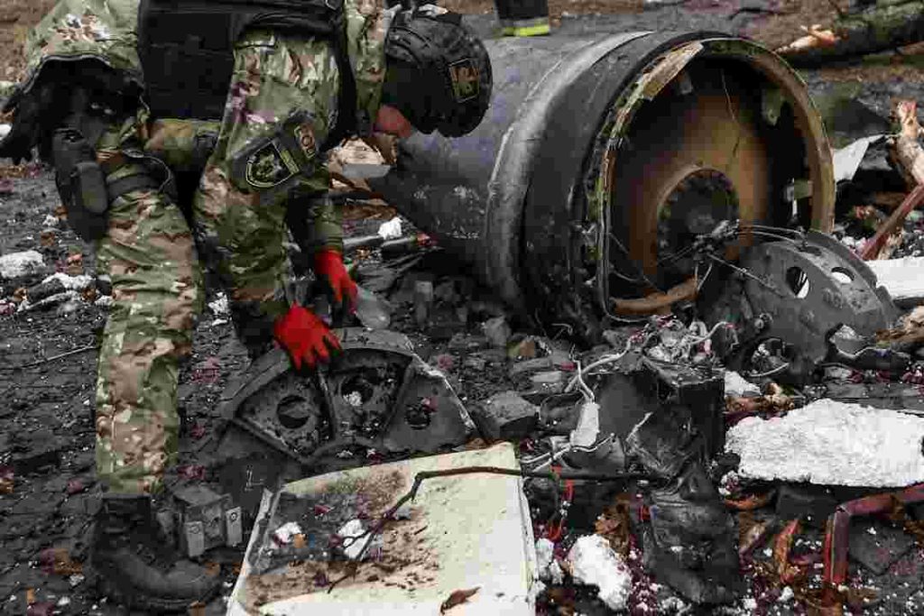 A bomb squad member works next to remains of an unidentified missile at the site where residential buildings were heavily damaged