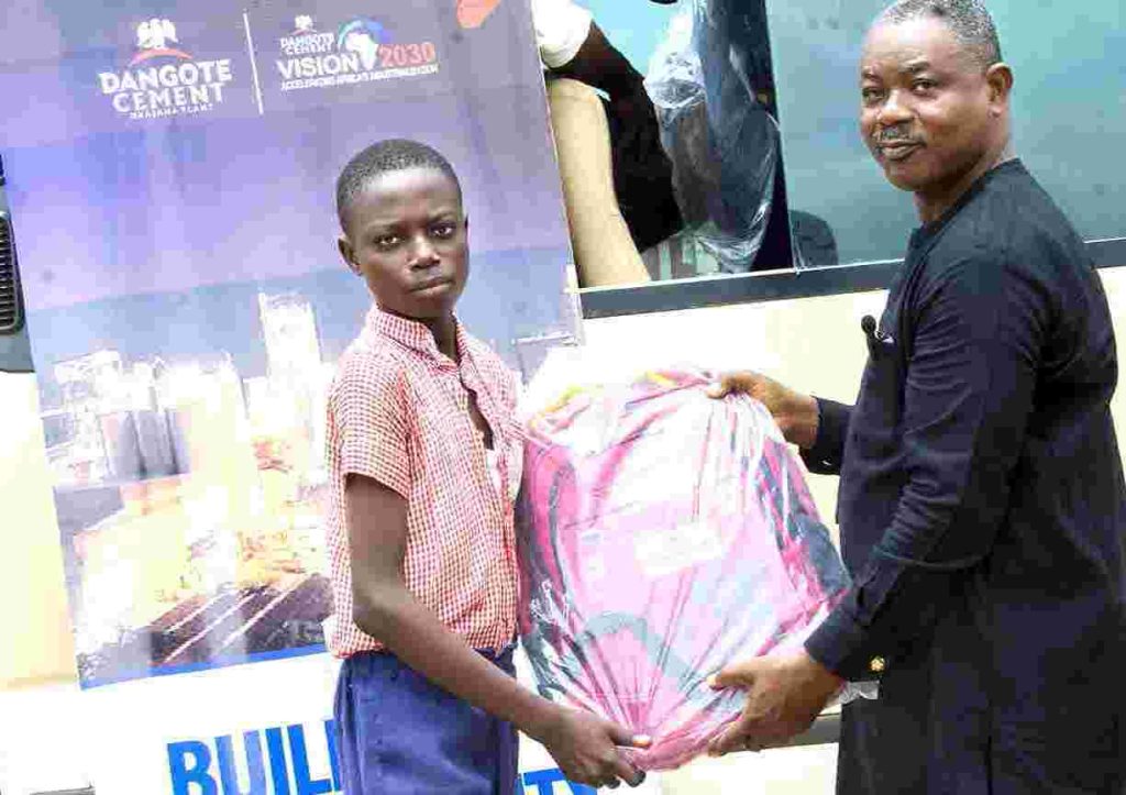 General Manager, Social Performance Department, Dangote Cement, Obajana Plant, Ademola Adeyemi, presents some learning materials to a pupil at the UBE LGEA School, St. Luke Model II, Adankolo, Lokoja LGA at the weekend.